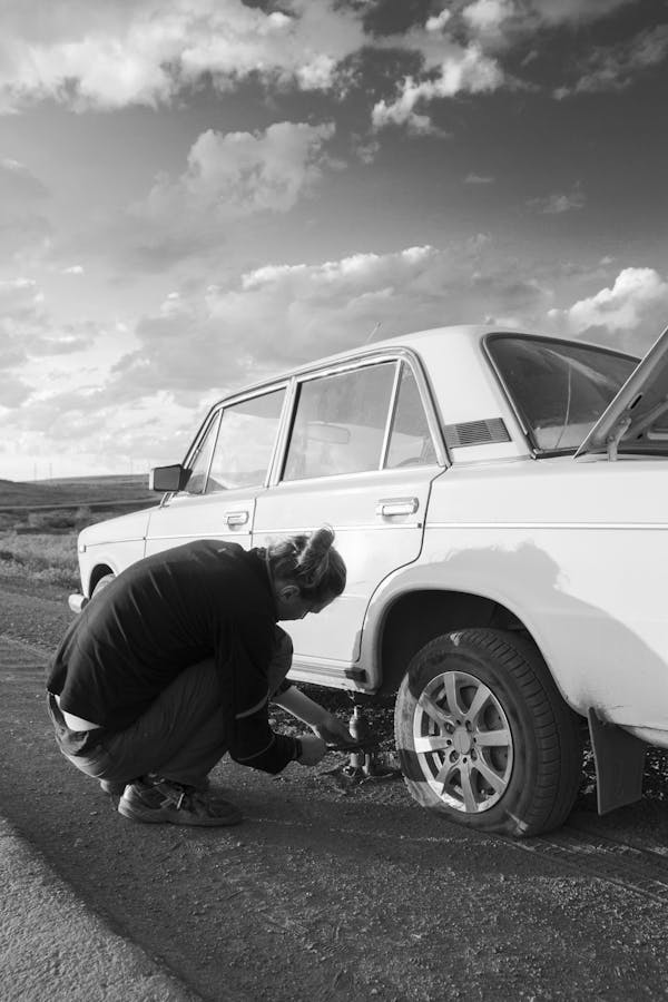 Person positioning the jack under the car frame to raise it